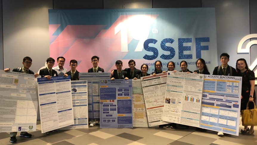Students holding research posters in front of a large SSEF Singapore Science and Engineering Fair banner.